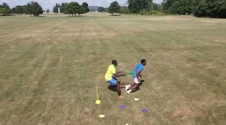Resistance Band Duel — Two athletes battling through resistance-band shielding work on the open field.