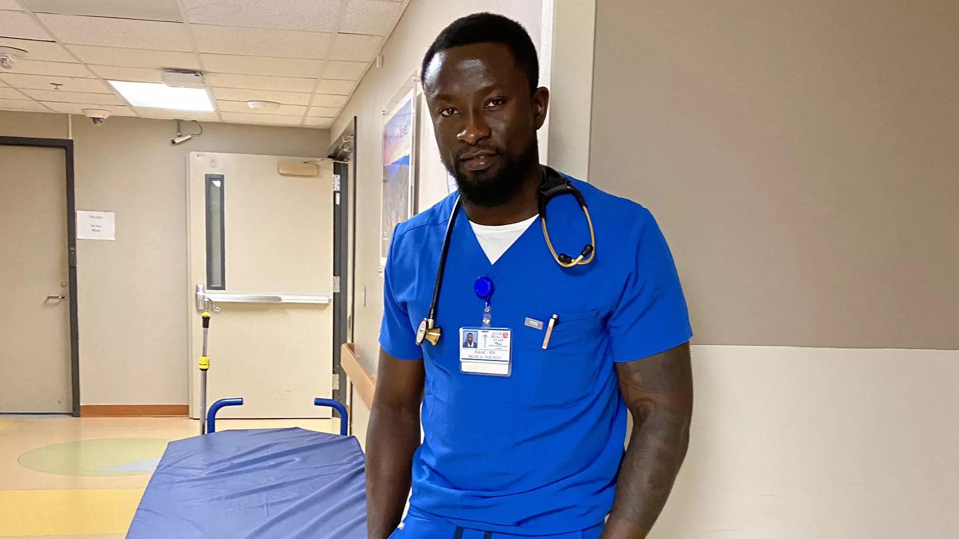 Isaac Kissi in scrubs working as a registered nurse