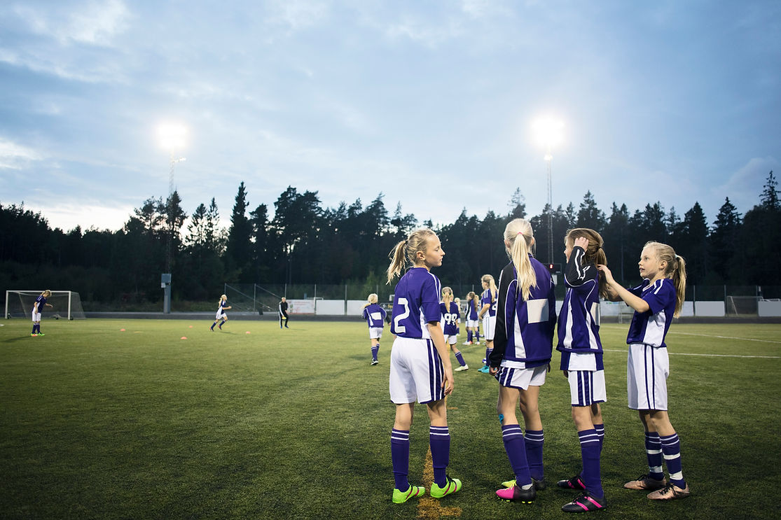 A coach talking to players during a training session in a large indoor sports facility.